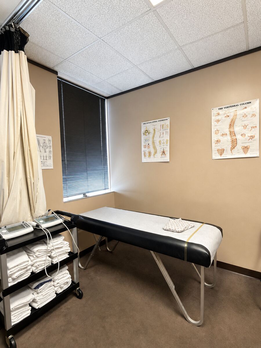 Exam room with treatment table, towel cart and spine charts